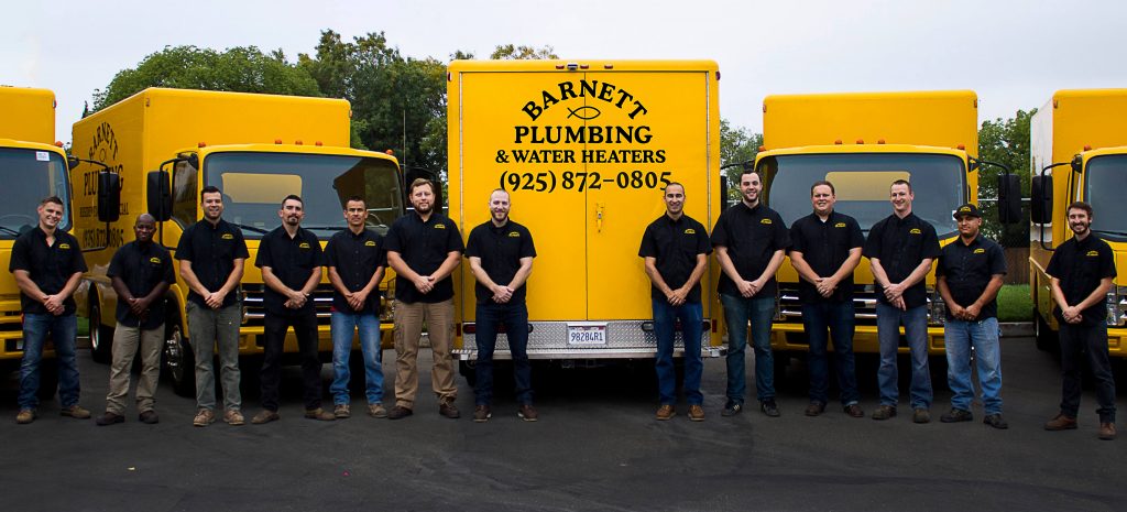 A group of men standing in front of Barnett plumbing and water heaters trucks