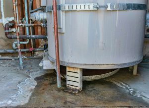 Corroded water heater tank leaks out the bottom and rusts