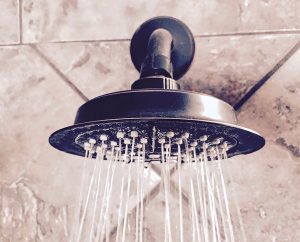 A black shower head with water coming out.