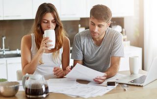 A man and a woman drinking coffee and looking over a pile of papers