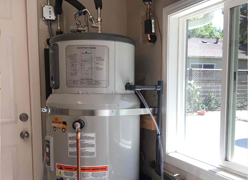 Hybrid water heater installed in a home, next to a sliding window.