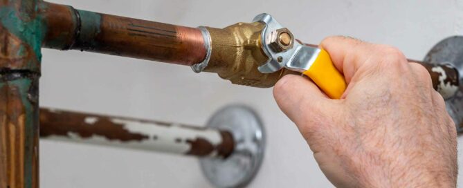 Person tightening a bolt on a water pipe