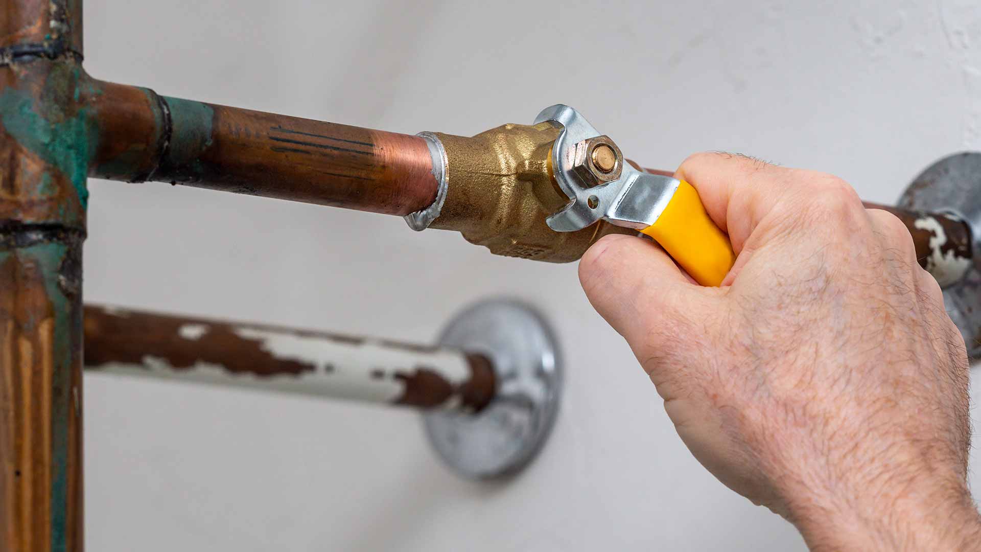 Person tightening a bolt on a water pipe