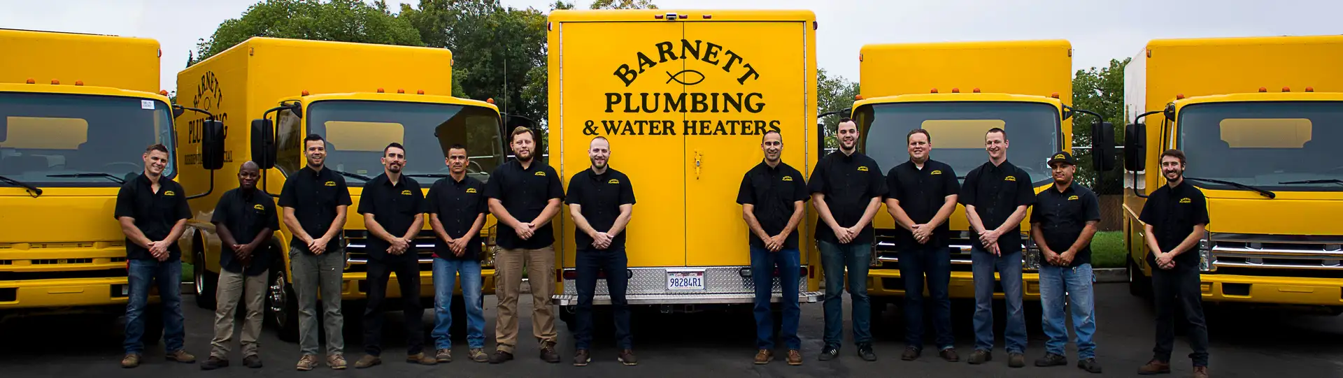 Barnett Plumbing & Water Heaters team standing in front of yellow service trucks