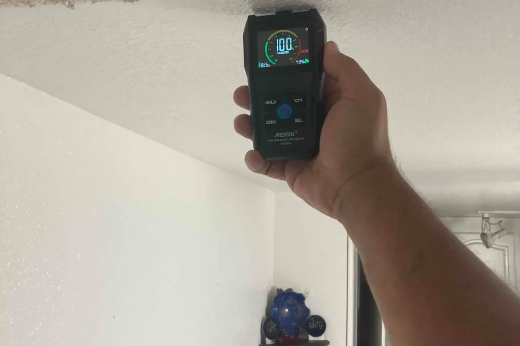 Plumber using a moisture meter on a wall during leak detection