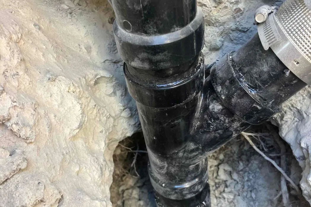 New black ABS sewer pipe installed in an excavated trench during a sewer line repair