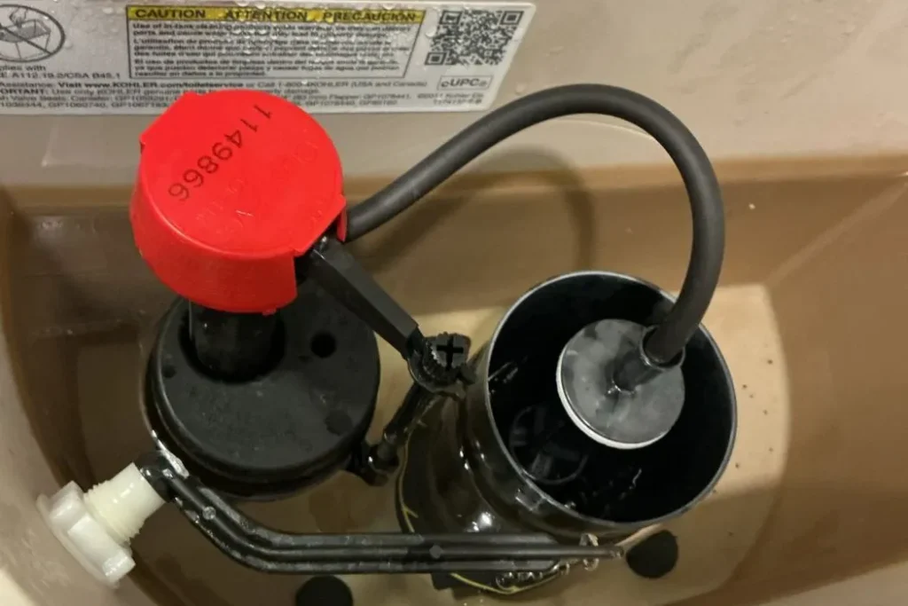 New fill valve and flapper installed inside a toilet tank during a toilet repair