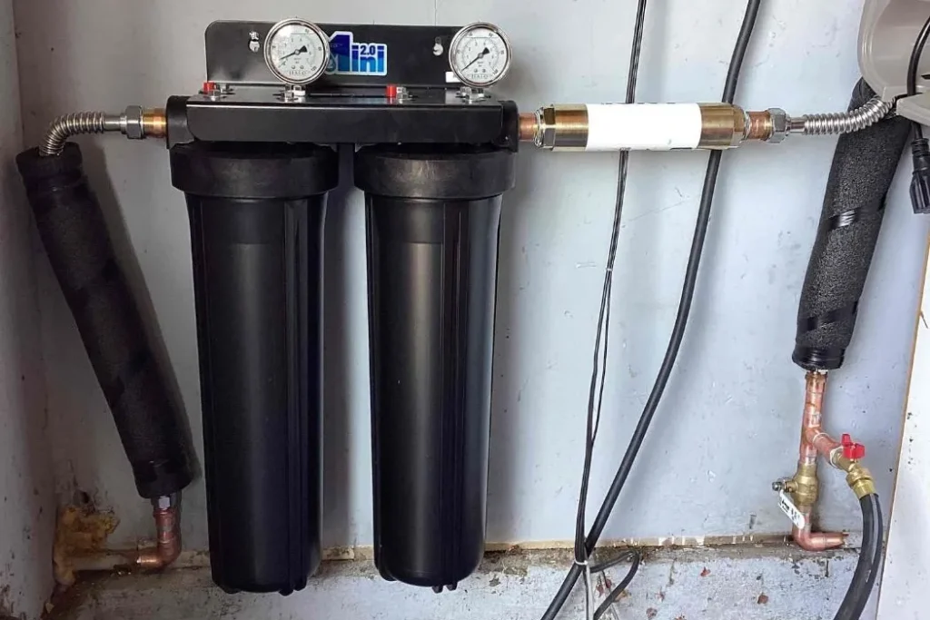 Whole-home water filtration system installed on copper water lines in a garage