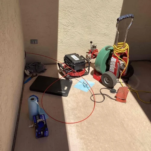 Sewer repair tools and equipment set up outdoors for sewer services, including a cable machine and cleaning supplies.
