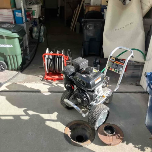 Equipment set up for sewer repair, highlighting essential sewer services in a garage with tools and open sewer access.