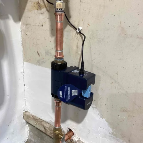 Copper pipes and a valve are installed on a wall for water line repair, showcasing modern plumbing equipment.